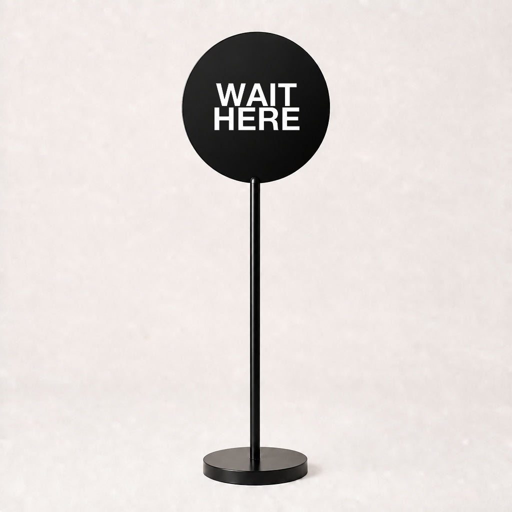 Black acrylic floor sign with WAIT HERE on the disc, example custom artwork